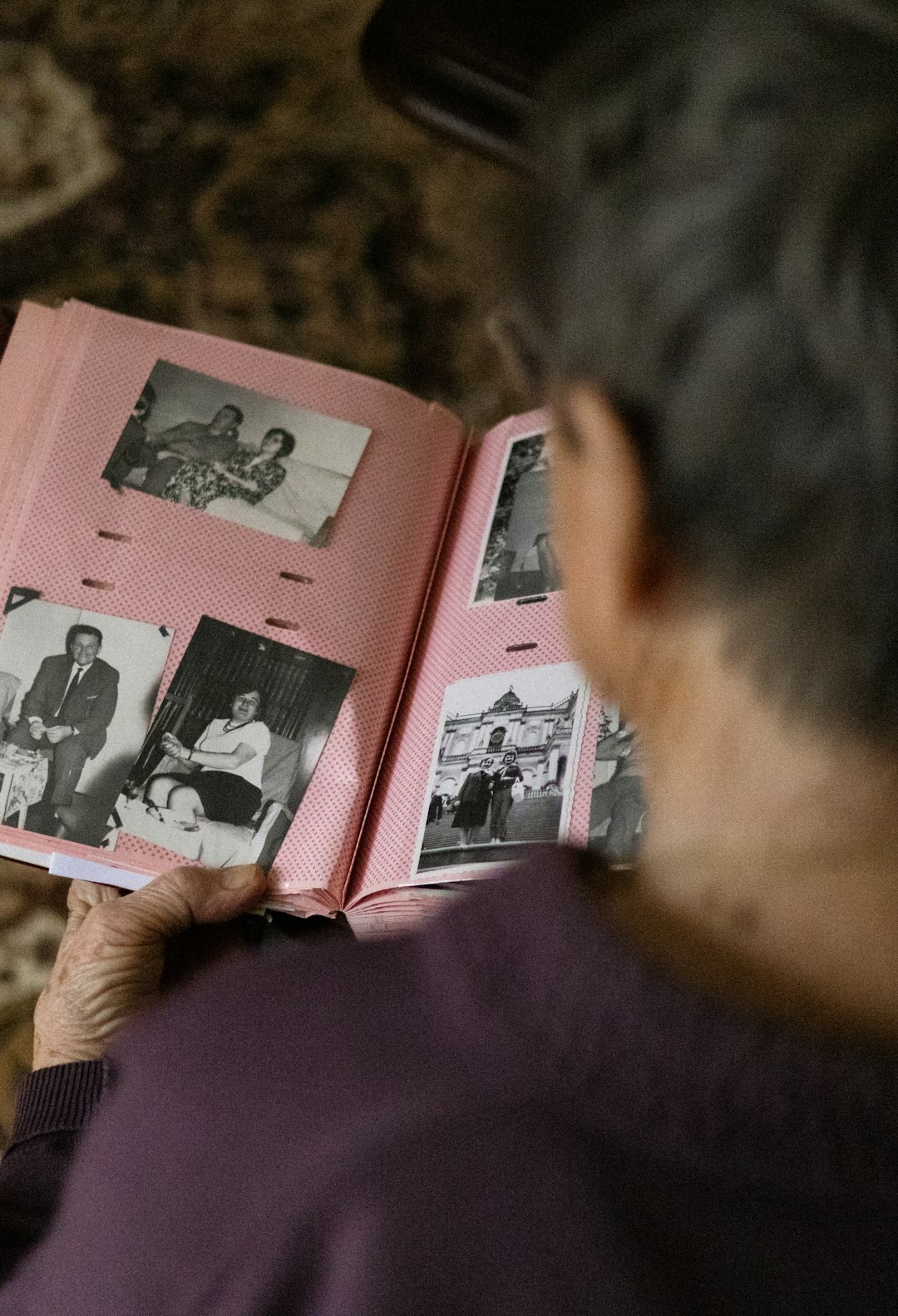 Elderly Danish woman looking through an old photo album at her kitchen table